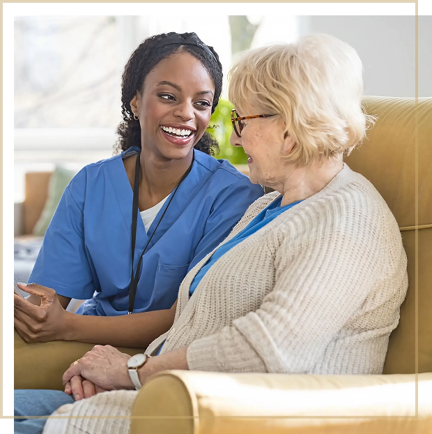 A nurse warmly interacting with an elderly woman in a cozy living room.